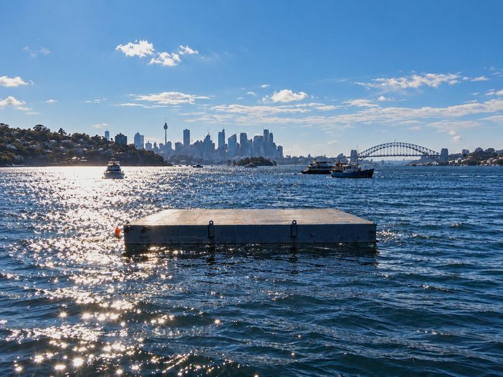 The 12 metre work barge on Sydney Harbour with the city skyline and harbour bridge behind